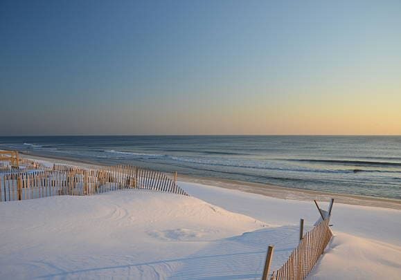 Snow covered beach and dunes at sunrise in New Jersey.